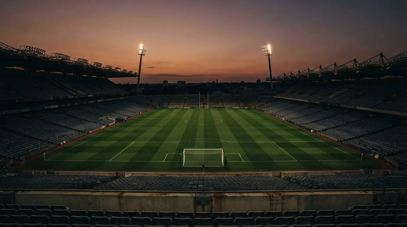 An empty football stadium with floodlight masts at dusk